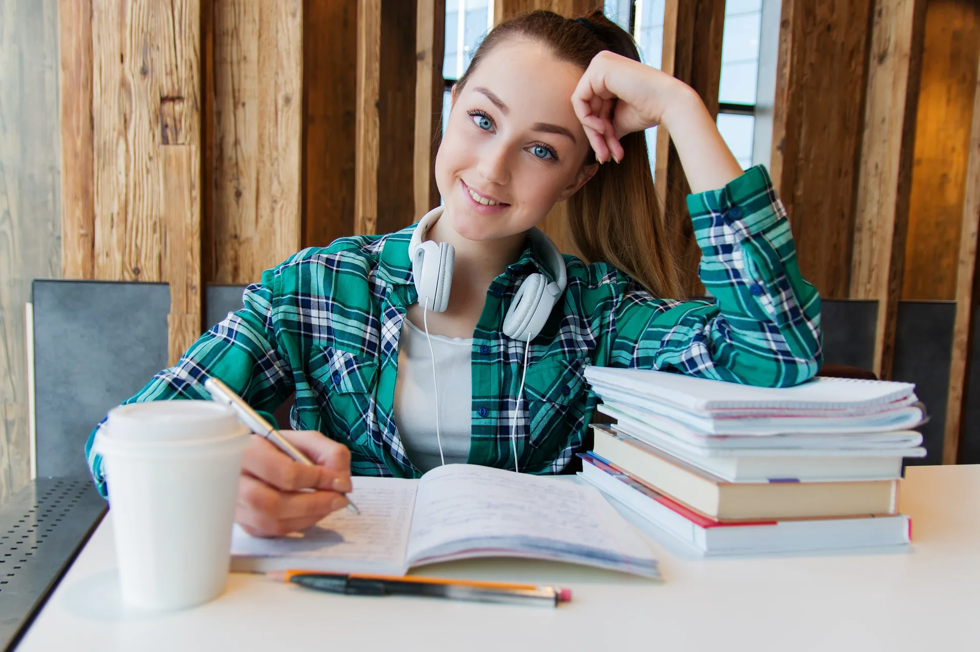 Girl student studying with headphones a notebook and coffee