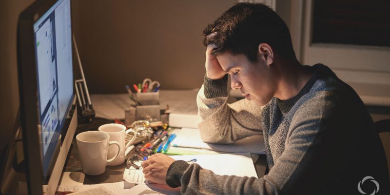 Motivating teenagers to study and avoid procrastination. Teenage student stressed and sitting at computer desk in the evening.